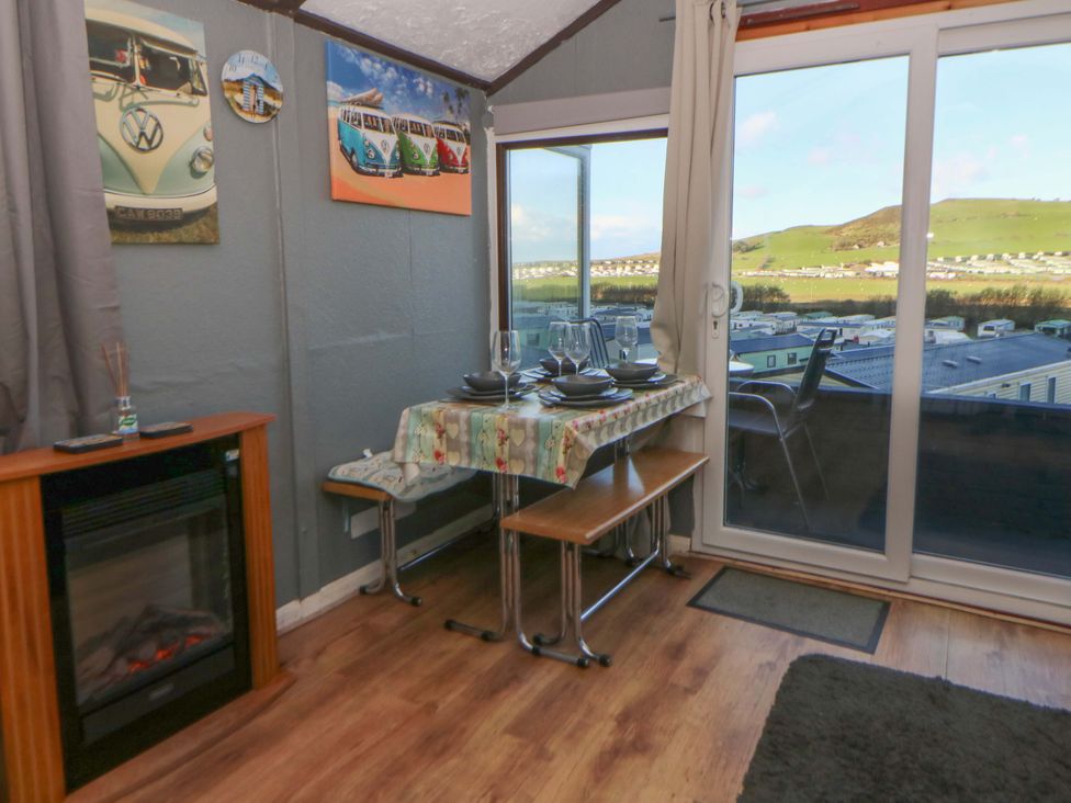 A dining room with a view and a fireplace at Captain's Cabin in Clarach Bay near Aberystwyth