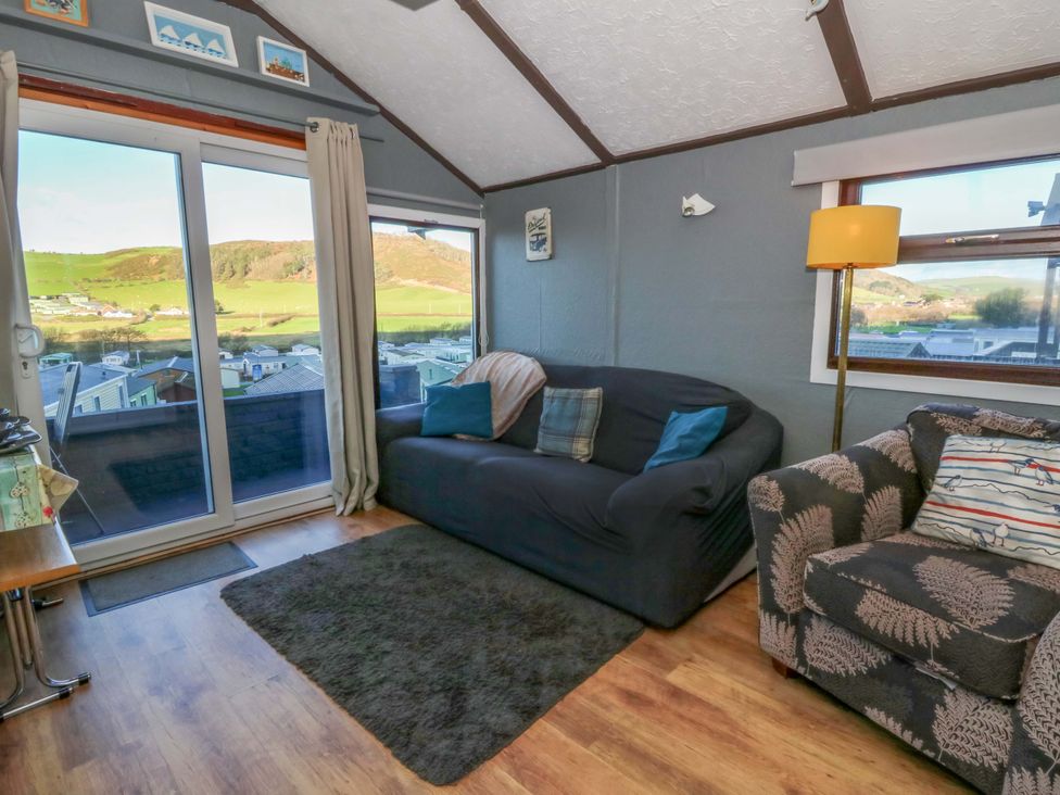 A living room with large windows and a sofa at Captain's Cabin, Clarach Bay near Aberystwyth
