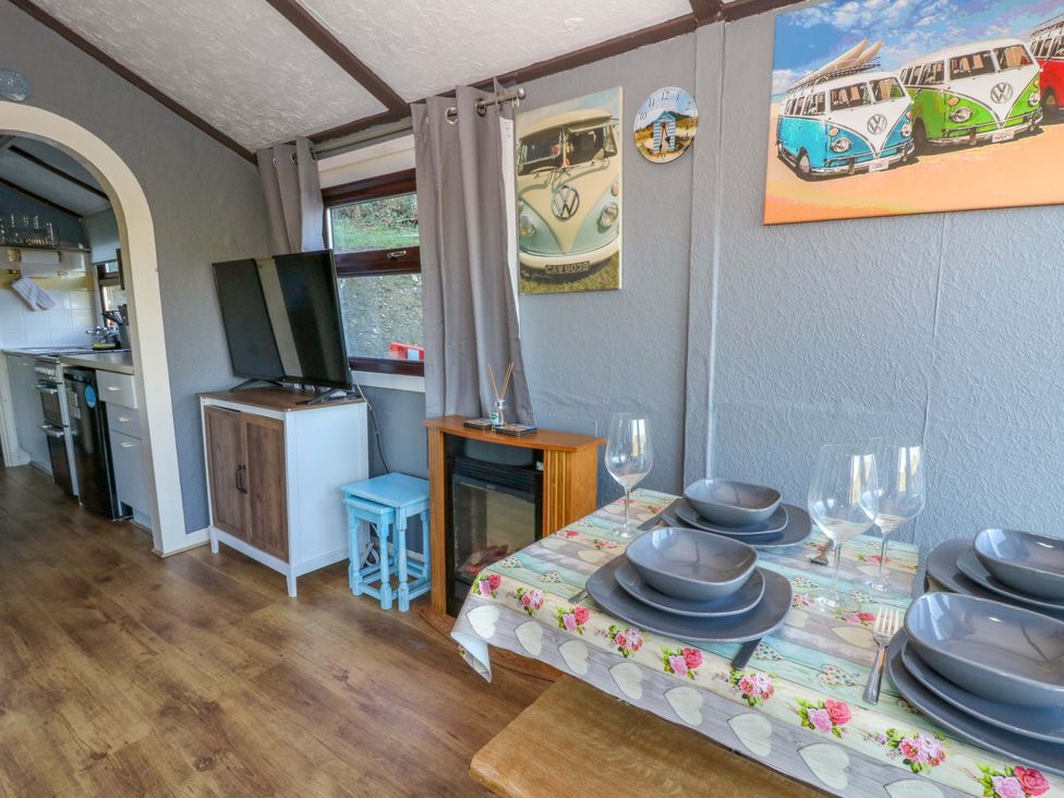 A dining area with a television and table set at Captain's Cabin in Clarach Bay near Aberystwyth