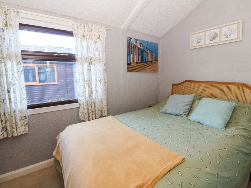 A bedroom with a bed and window at Captain's Cabin in Clarach Bay near Aberystwyth