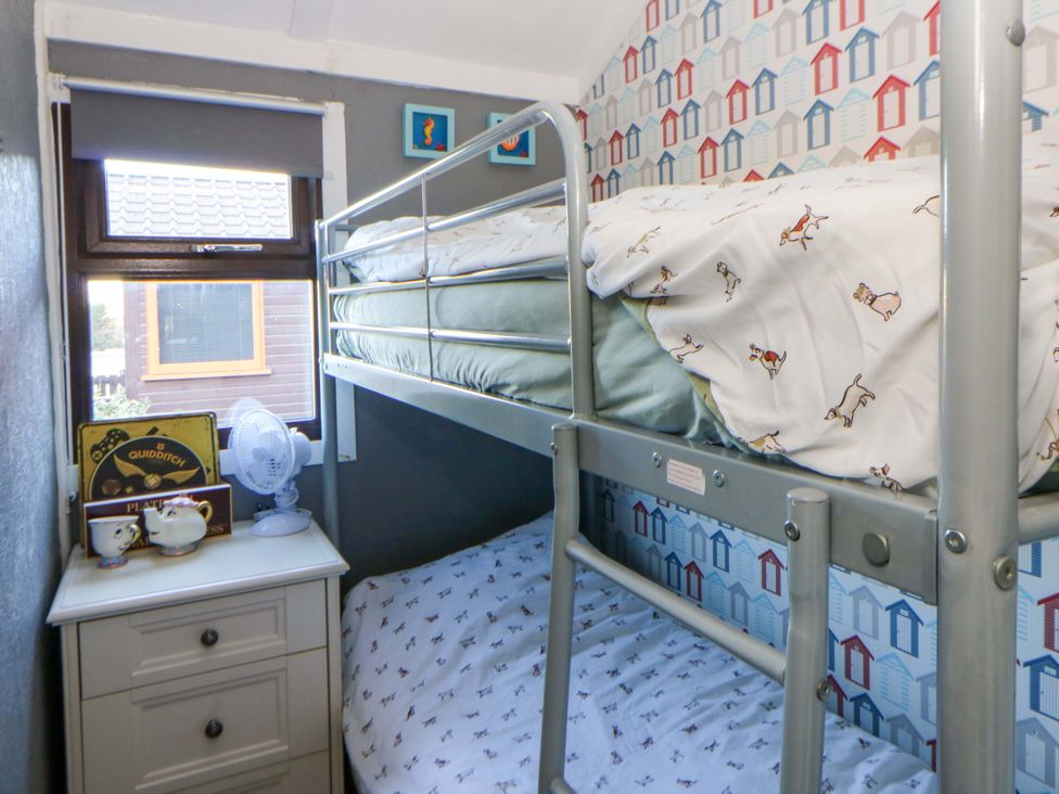 A bedroom with a bunk bed and nightstand at Captain's Cabin in Clarach Bay near Aberystwyth