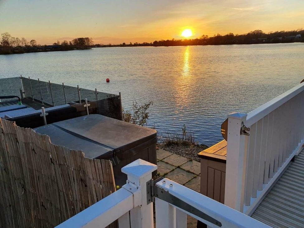 a lake view with sunset and a wooden fence at Tattershall Lakes Country Park - Holiday Accommodation 16408 in Tattershall