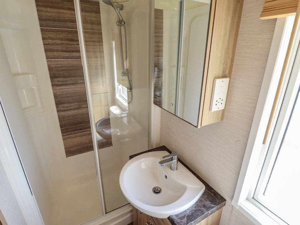 A bathroom with a shower, sink, and mirror at Tattershall Lakes Country Park - Holiday Accommodation 16408, Tattershall