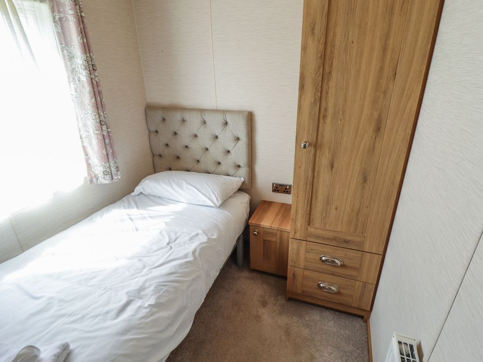 A bedroom with a bed and wooden furniture at Tattershall Lakes Country Park - Holiday Accommodation 16408 in Tattershall