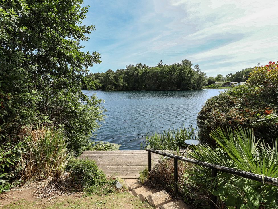 A view of water with a wooden deck and surrounding plants at Tattershall Lakes Country Park - Holiday Accommodation 16408 Tattershall