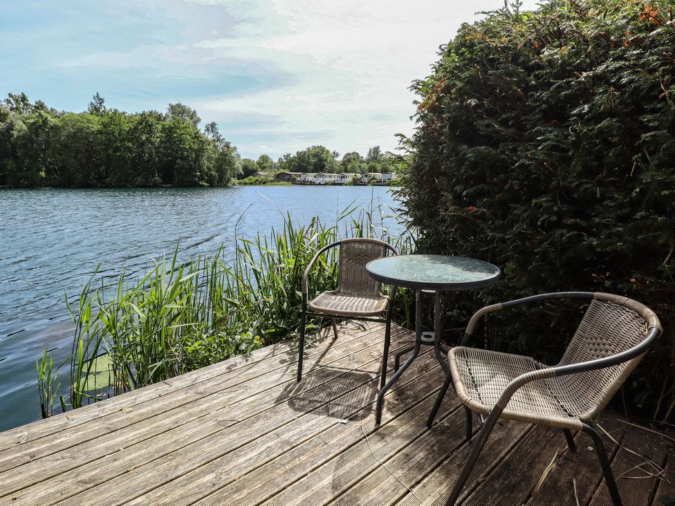 An outdoor area with two chairs and a table by the lake at Tattershall Lakes Country Park - Holiday Accommodation 16408 Tattershall