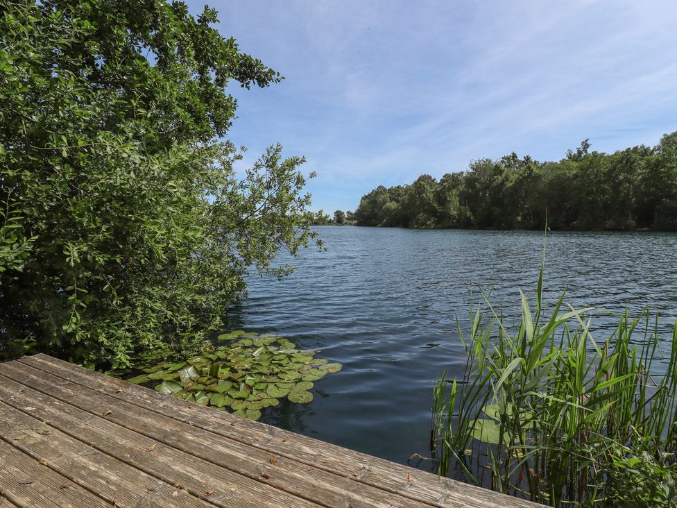 A view of water with a wooden deck and surrounding plants at Tattershall Lakes Country Park - Holiday Accommodation 16408, Tattershall