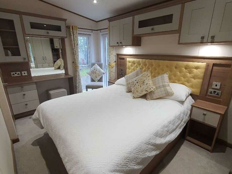 a bedroom with a double bed, fitted cabinets, and a mirror at Tattershall Lakes Country Park - Holiday Accommodation 16605 in Tattershall