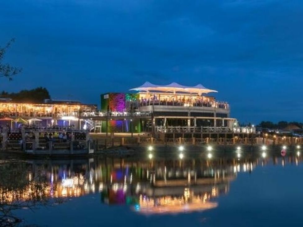 a lakeside building with outdoor seating illuminated at night at Tattershall Lakes Country Park - Holiday Accommodation 16605 Tattershall