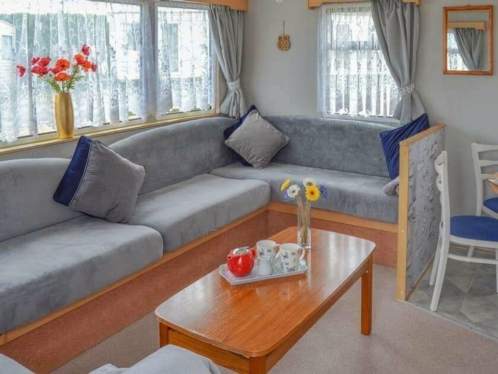 a living room with a grey sectional couch and wooden coffee table at Beach Haven Caravan Park - Holiday Accommodation 16700, Bacton