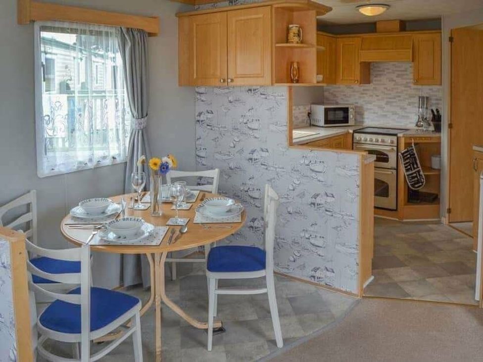 a dining area with a round table and four chairs in Beach Haven Caravan Park - Holiday Accommodation 16700, Bacton