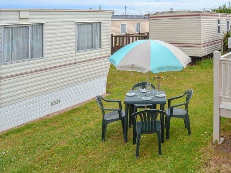 a table and chairs under an umbrella in a grassy area at Beach Haven Caravan Park - Holiday Accommodation 16700 Bacton