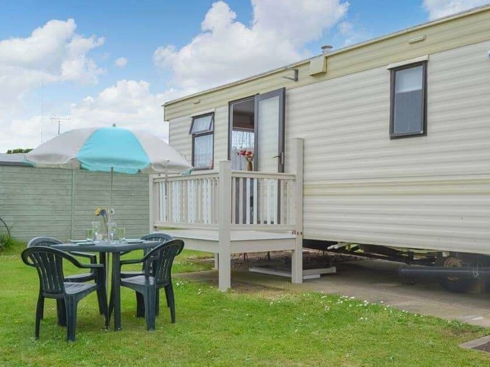 a caravan with a deck and seating area at Beach Haven Caravan Park - Holiday Accommodation 16700 Bacton