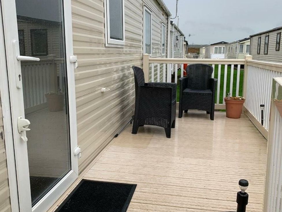 a porch with two chairs and a potted plant at Alberta Holiday Park - Holiday Accommodation 16770 in Whitstable