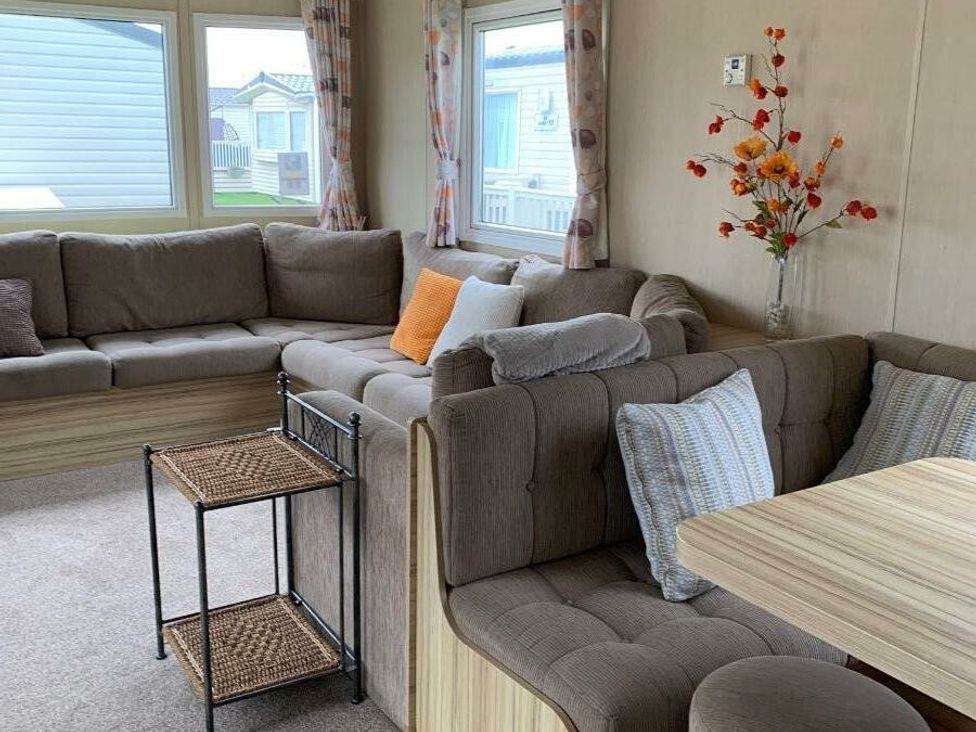 a seating area with a sectional sofa and a small table at Alberta Holiday Park - Holiday Accommodation 16770 in Whitstable