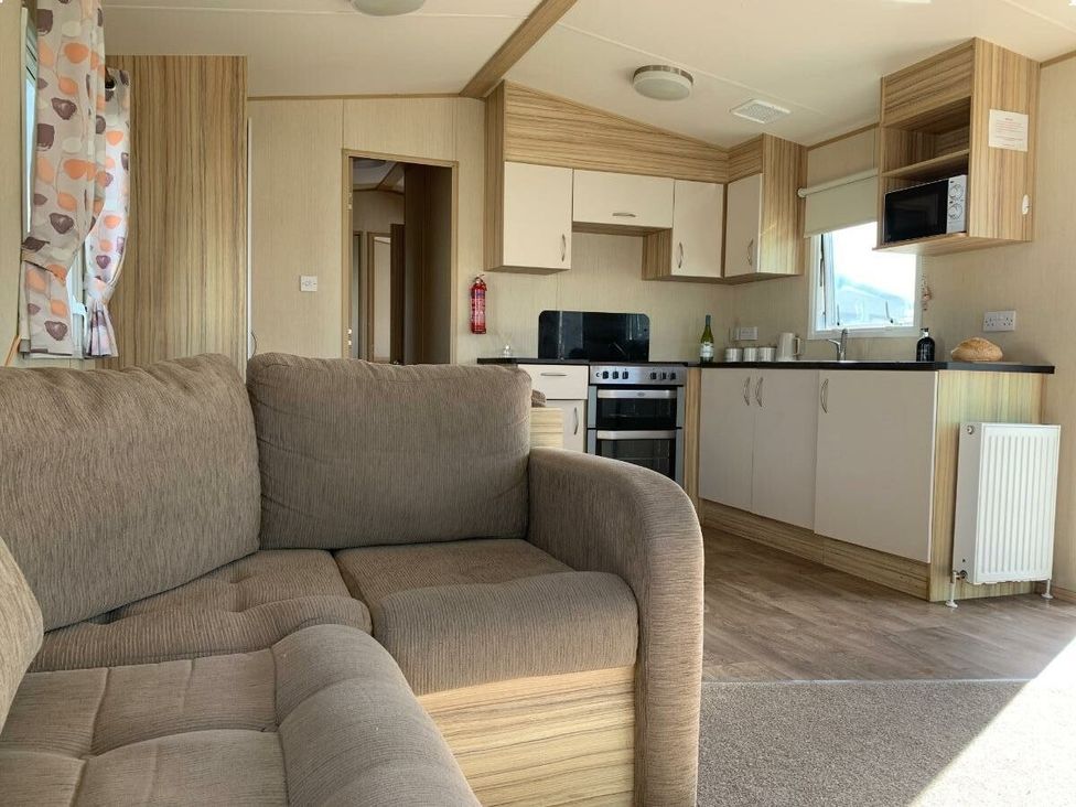 a living room with a sofa and kitchen area at Alberta Holiday Park - Holiday Accommodation 16770 in Whitstable