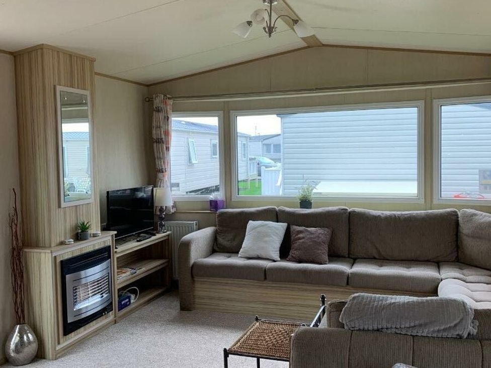 a living room with a sofa, television, and windows at Alberta Holiday Park - Holiday Accommodation 16770, Whitstable
