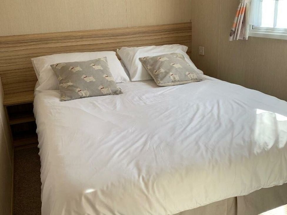 a bedroom with a bed and decorative pillows at Alberta Holiday Park - Holiday Accommodation 16770 in Whitstable