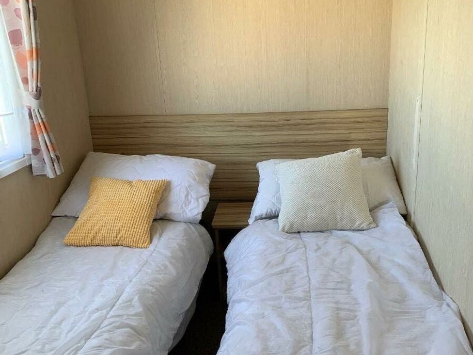a bedroom with two single beds and pillows at Alberta Holiday Park - Holiday Accommodation 16770 in Whitstable
