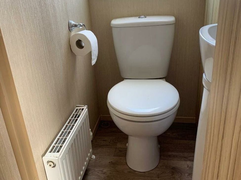 a small bathroom with a toilet, radiator, and sink at Alberta Holiday Park - Holiday Accommodation 16770, Whitstable