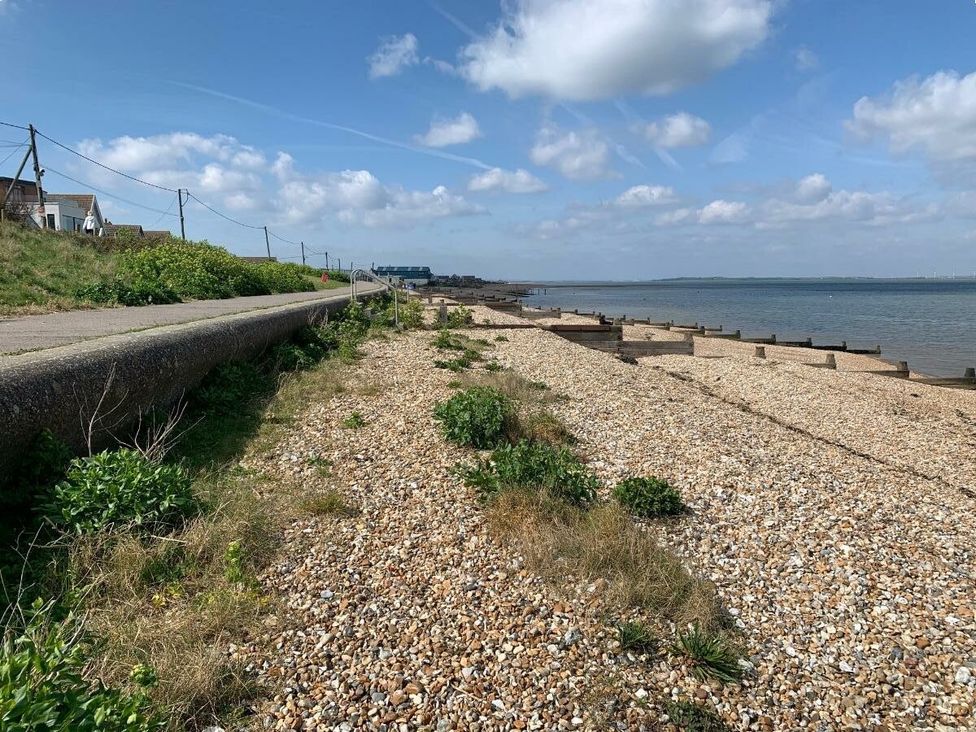 a pebbled beach with a path and grassy areas at Alberta Holiday Park - Holiday Accommodation 16770, Whitstable