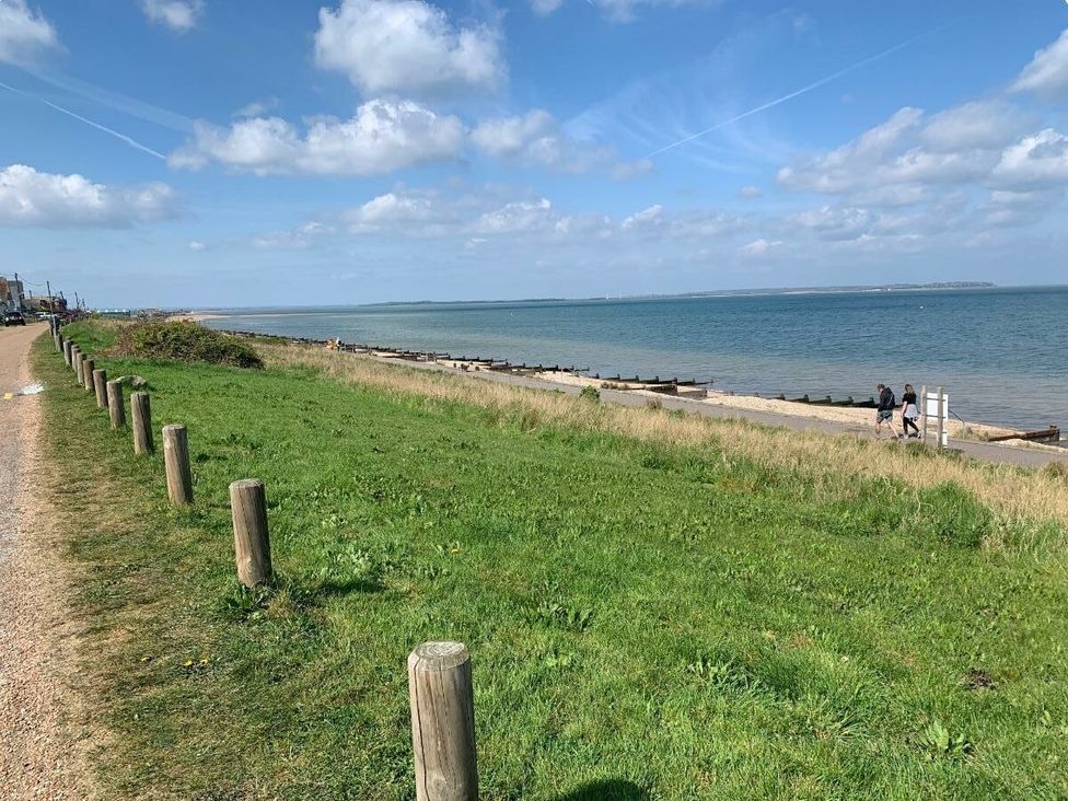 a coastal view with a grass area and a pathway leading along the water at Alberta Holiday Park - Holiday Accommodation 16770 Whitstable