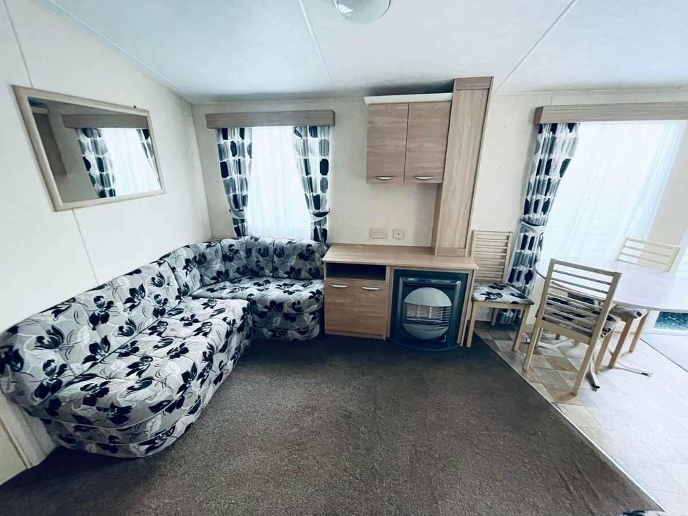 a lounge area with a patterned sofa, table, and chair at WigBay Holiday Park - Holiday Accommodation 16774, Stranraer