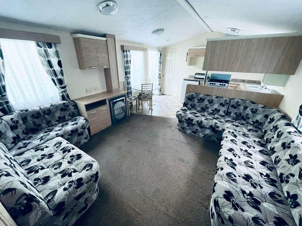 a living room with patterned couches and a kitchenette at WigBay Holiday Park - Holiday Accommodation 16774, Stranraer