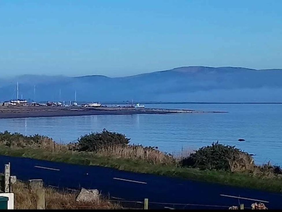a coastal view featuring water, hills, and boats with a road in the foreground at WigBay Holiday Park - Holiday Accommodation 16774 Stranraer