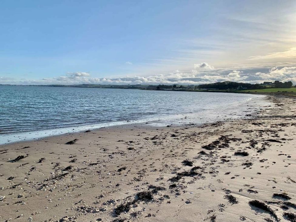 a beach with sand and seaweed by the water at WigBay Holiday Park - Holiday Accommodation 16774 in Stranraer