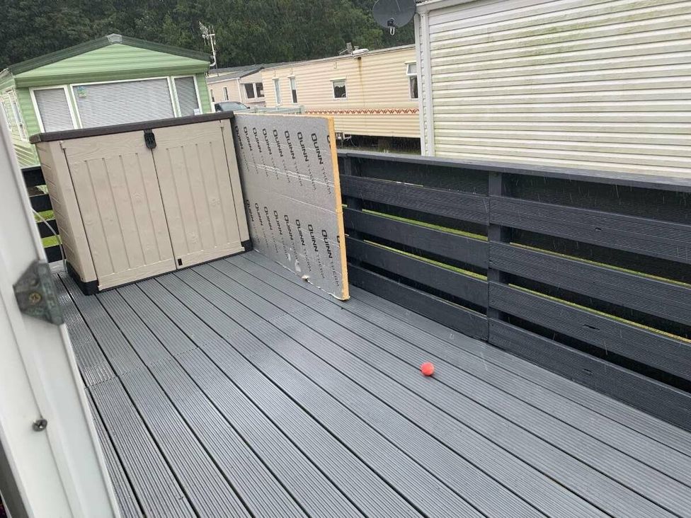 an outdoor deck with a storage box and a red ball at WigBay Holiday Park - Holiday Accommodation 16774 in Stranraer