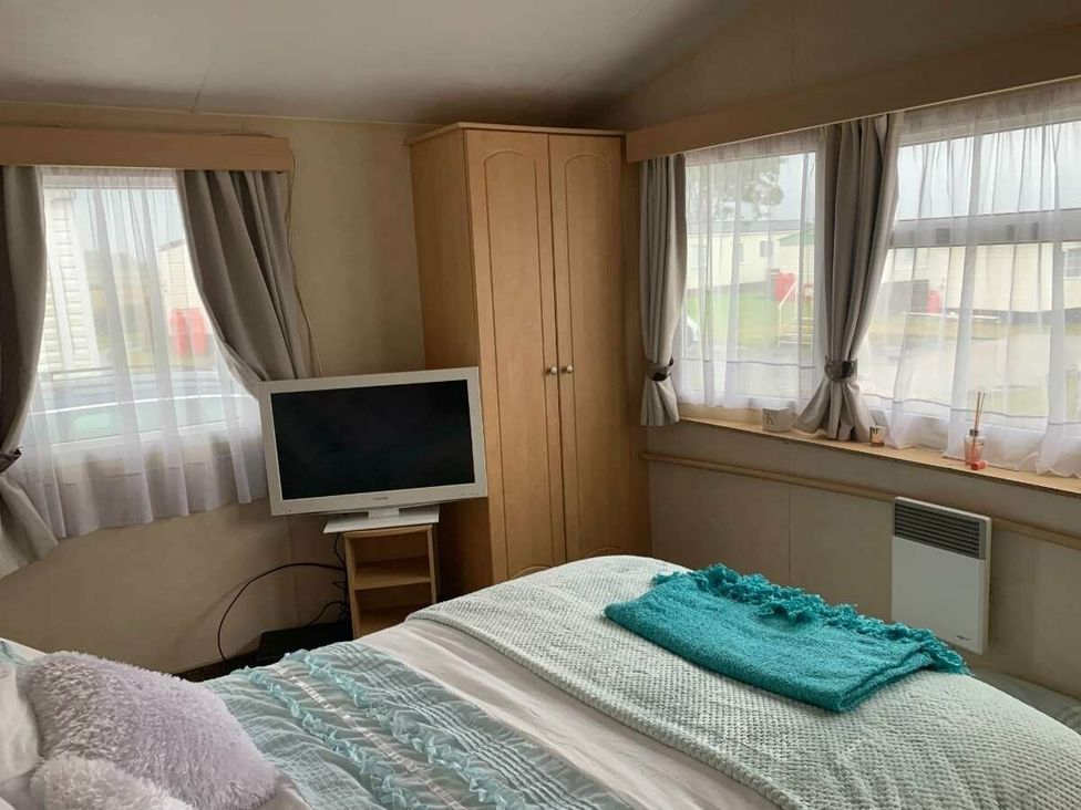 a bedroom with a television and curtains at WigBay Holiday Park - Holiday Accommodation 16774 Stranraer