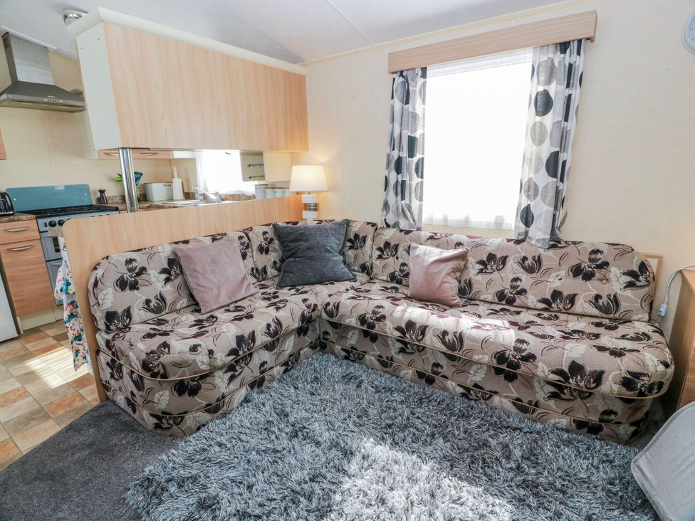 A living room with a sofa and kitchen appliances at WigBay Holiday Park - Holiday Accommodation 16774, Stranraer
