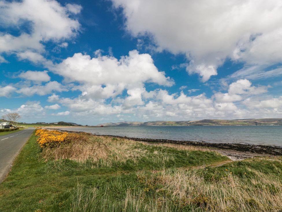 A scenic view of the shoreline with grass and a road at WigBay Holiday Park - Holiday Accommodation 16774 Stranraer