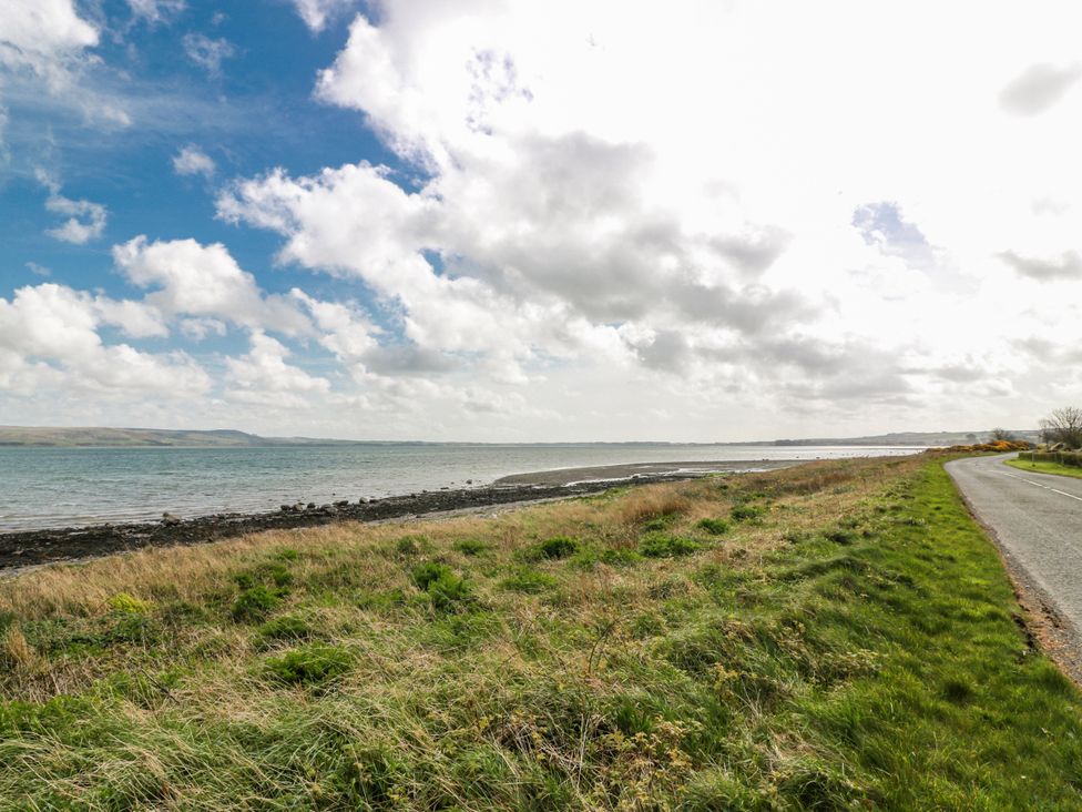 A shoreline with water and grass beside a road at WigBay Holiday Park - Holiday Accommodation 16774, Stranraer