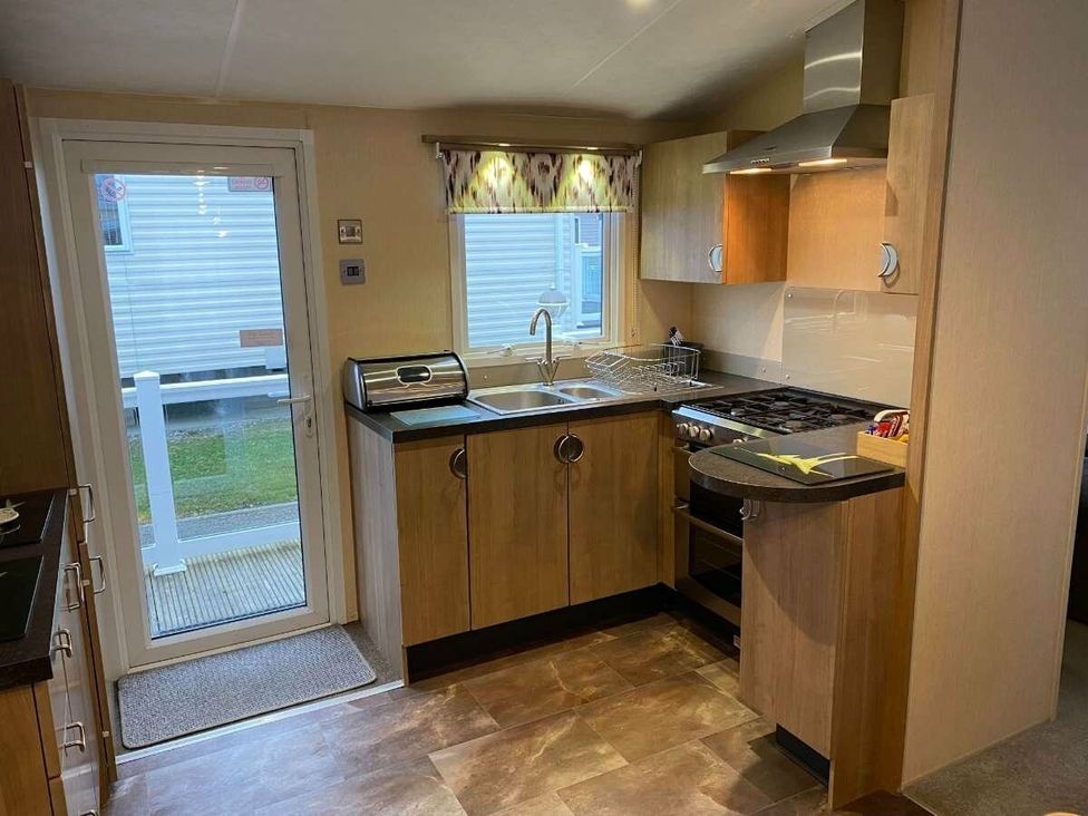 a kitchen with wooden cabinets and a sink at Chesil Beach Holiday Park - Holiday Accommodation 16933 in Weymouth