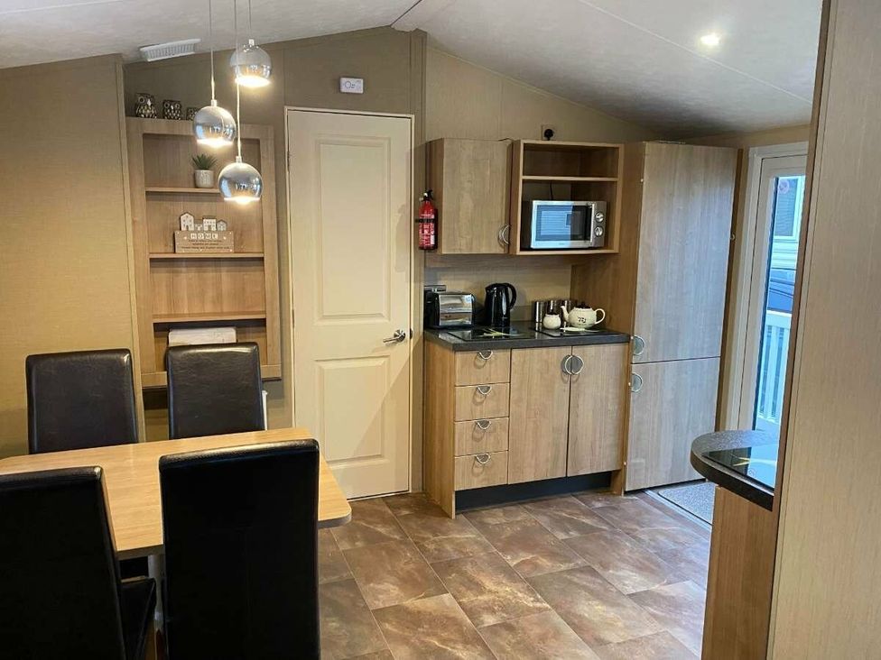 a kitchen area with cabinets, a microwave, and a coffee maker at Chesil Beach Holiday Park - Holiday Accommodation 16933 in Weymouth
