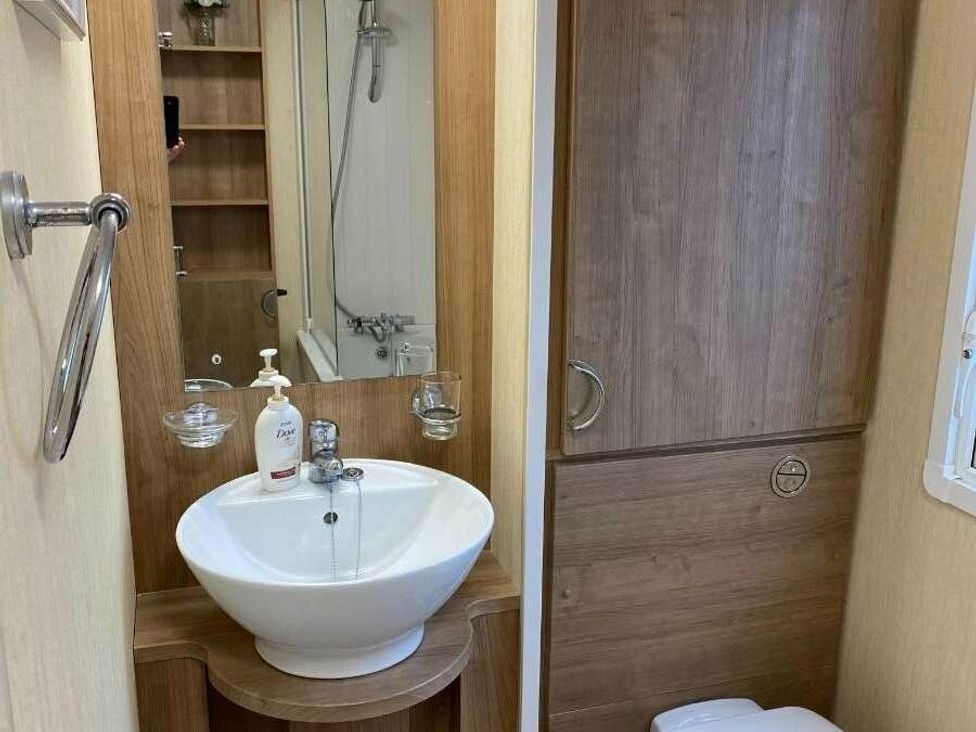 a bathroom with a sink, mirror, and shower at Chesil Beach Holiday Park - Holiday Accommodation 16933, Weymouth