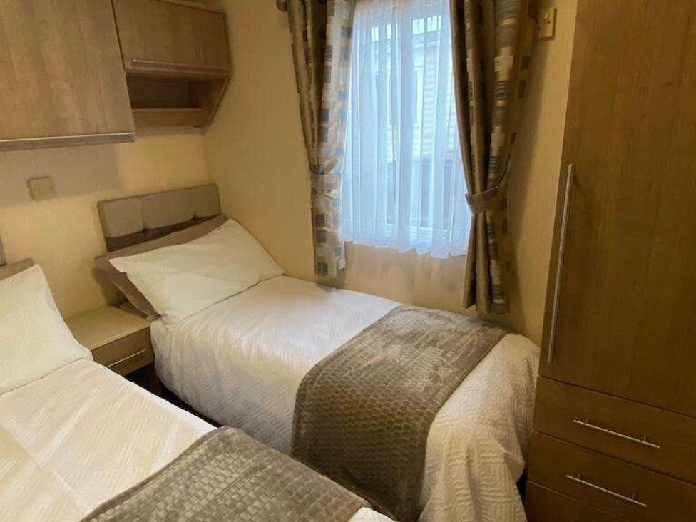 a bedroom with two beds and a window with curtains at Chesil Beach Holiday Park - Holiday Accommodation 16933, Weymouth