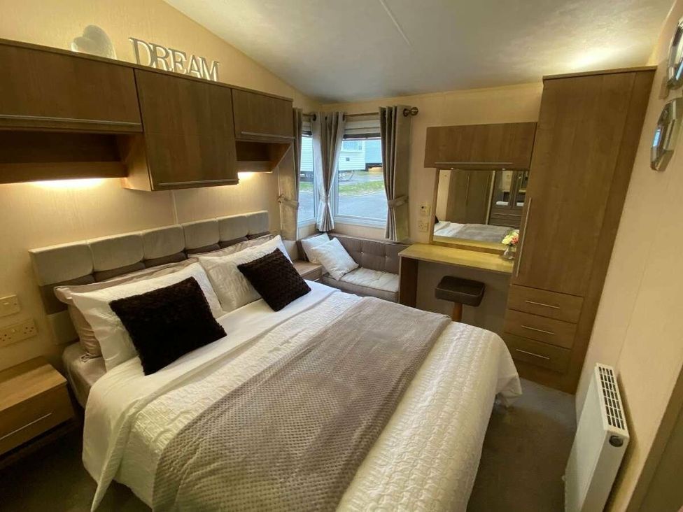 a bedroom with a double bed and wooden furniture at Chesil Beach Holiday Park - Holiday Accommodation 16933 in Weymouth