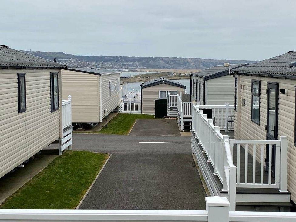 a pathway between holiday caravans with a view of the coast at Chesil Beach Holiday Park - Holiday Accommodation 16933 in Weymouth