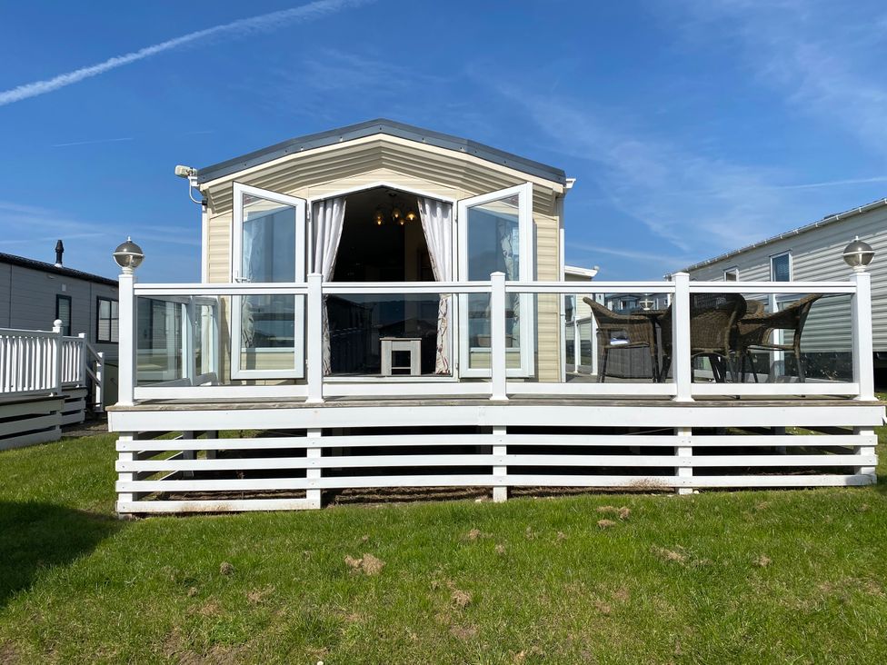 A deck with chairs and a door at Chesil Beach Holiday Park - Holiday Accommodation 16933, Weymouth