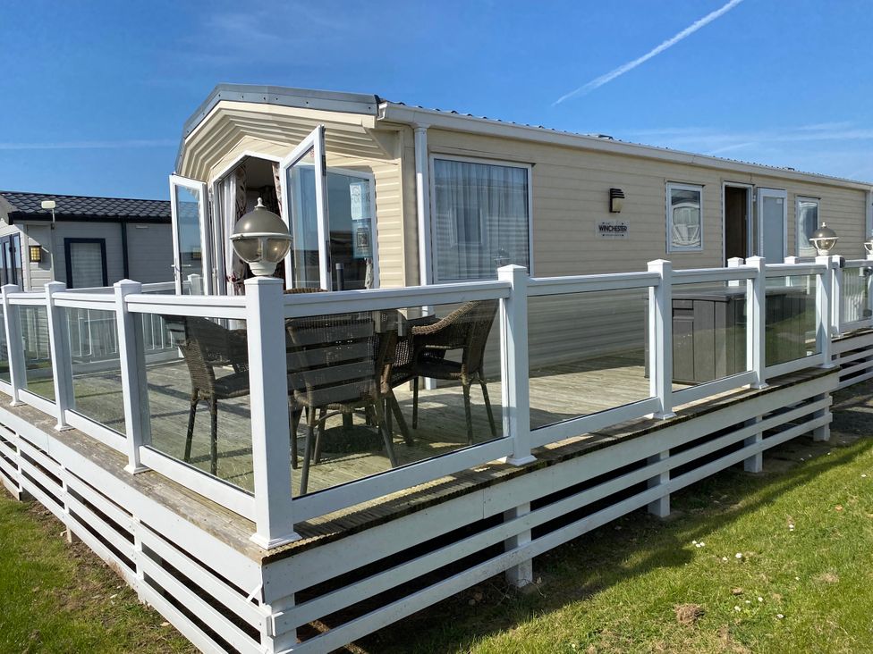 A mobile home with a deck and seating area at Chesil Beach Holiday Park - Holiday Accommodation 16933 Weymouth