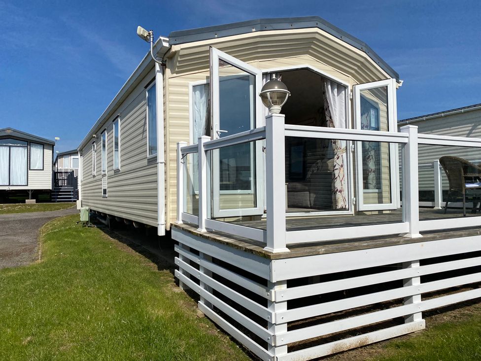 A caravan with a deck and a railing at Chesil Beach Holiday Park - Holiday Accommodation 16933, Weymouth