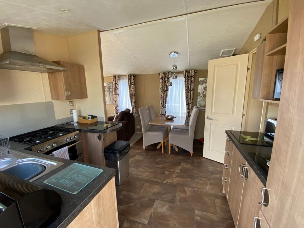 A kitchen with an oven, sink, and dining table at Chesil Beach Holiday Park - Holiday Accommodation 16933, Weymouth