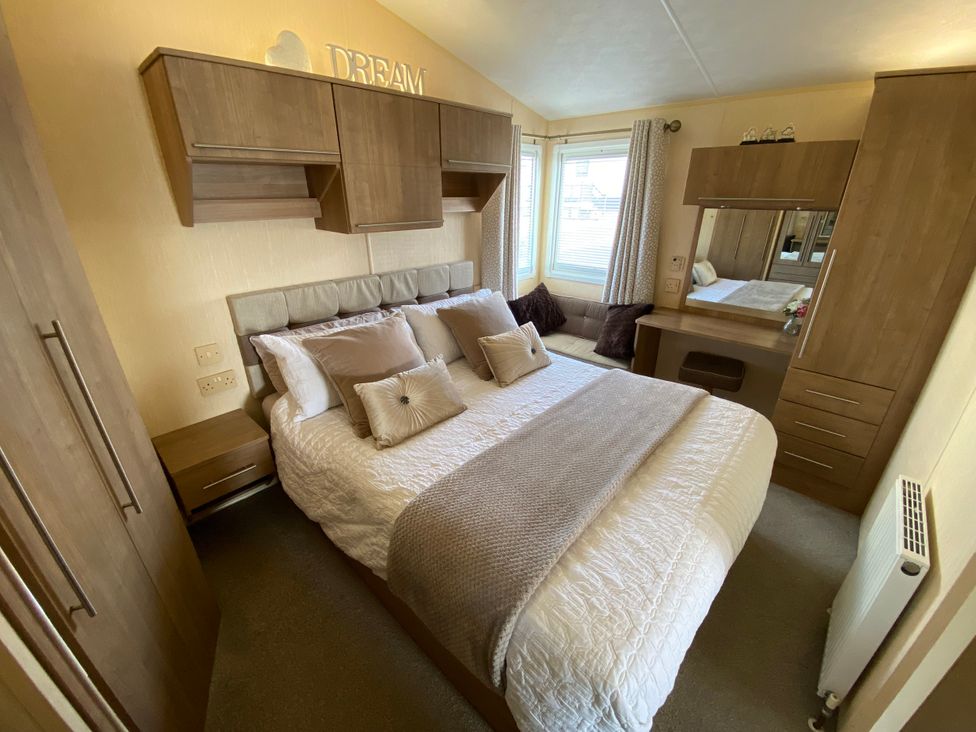 A bedroom with a bed, wardrobe, and dressing table at Chesil Beach Holiday Park - Holiday Accommodation 16933, Weymouth