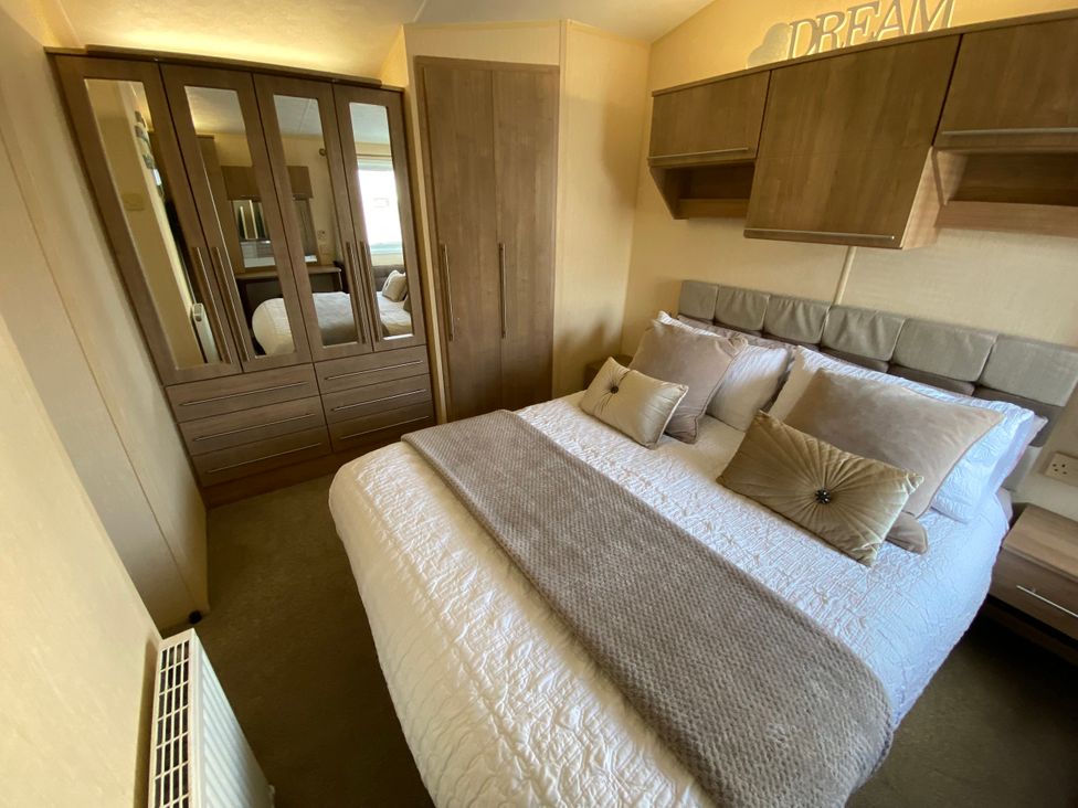 A bedroom with a bed and wardrobe at Chesil Beach Holiday Park - Holiday Accommodation 16933, Weymouth