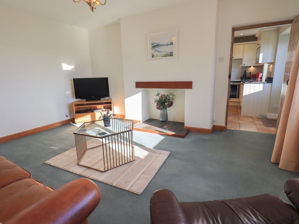 A living room with a TV and coffee table at 2 Lupton Hall Cottages in Carnforth
