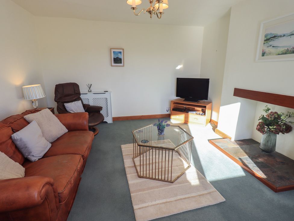 A living room with a sofa and television at 2 Lupton Hall Cottages Carnforth