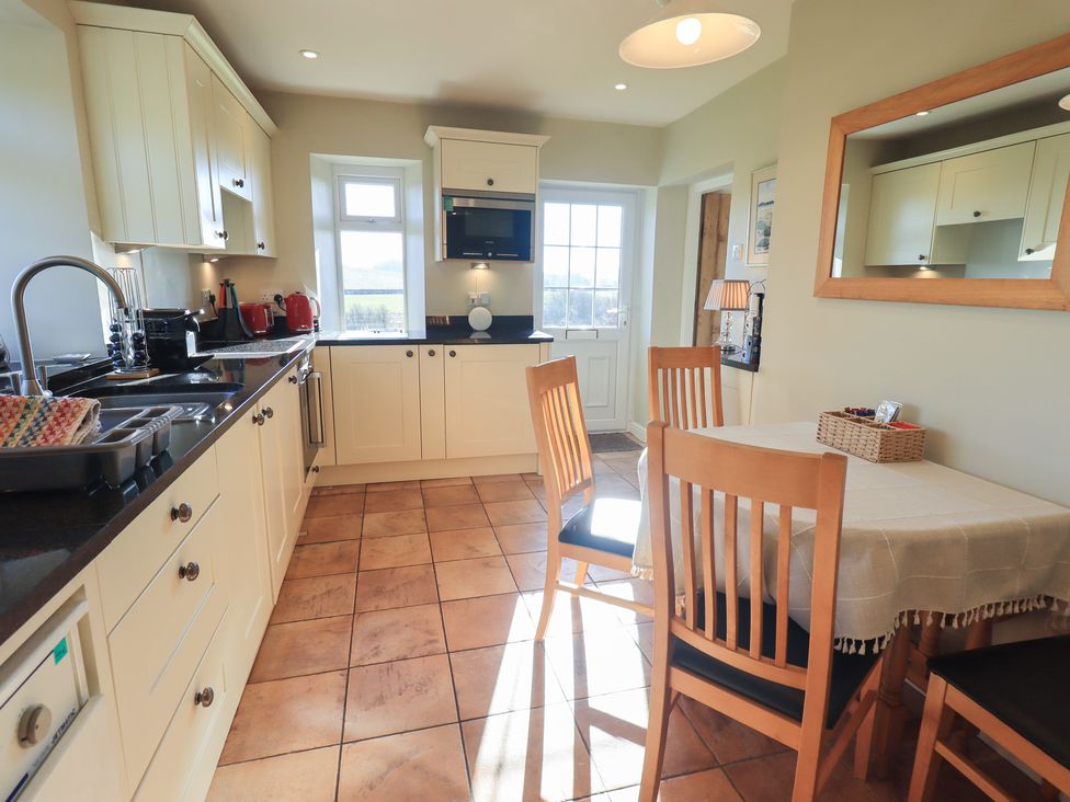 A kitchen with dining table and appliances at 2 Lupton Hall Cottages in Carnforth